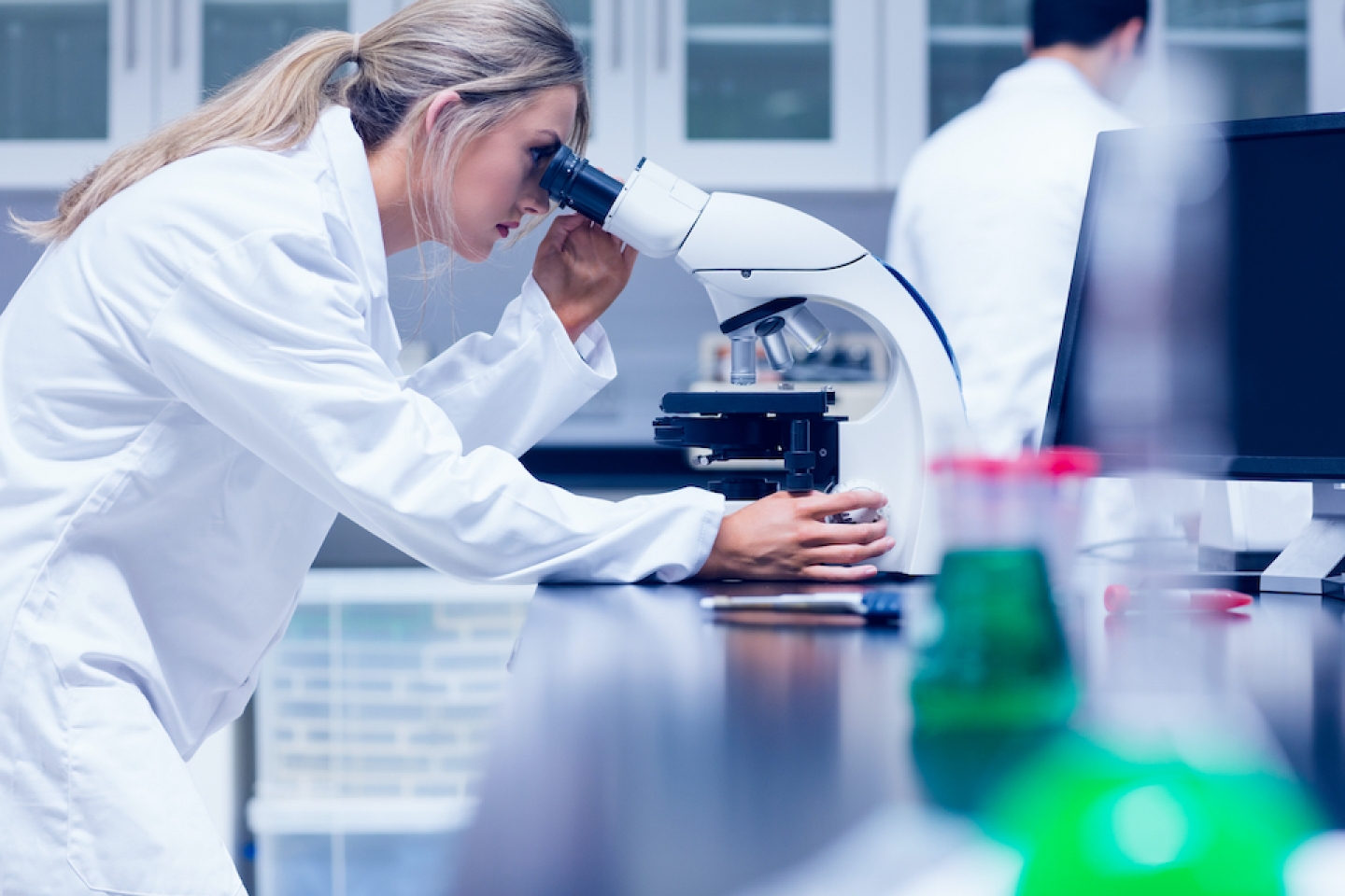 scientist in lab reviewing microscope