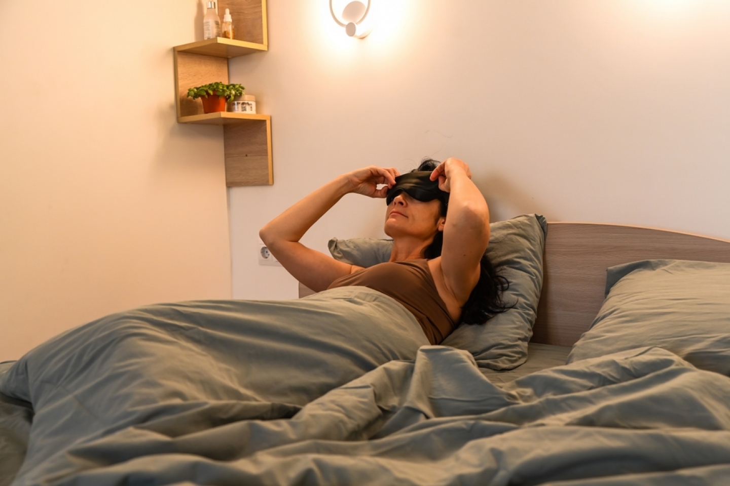 woman with blindfold trying to sleep in bed