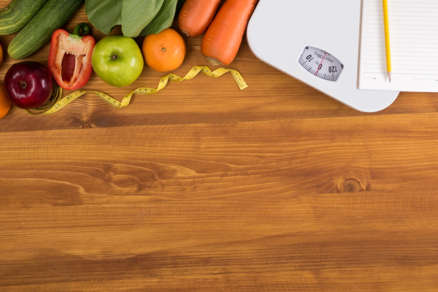 Fitness and weight loss concept, dumbbells, white scale, fruit and tape measure on a wooden table, top view, free copy space