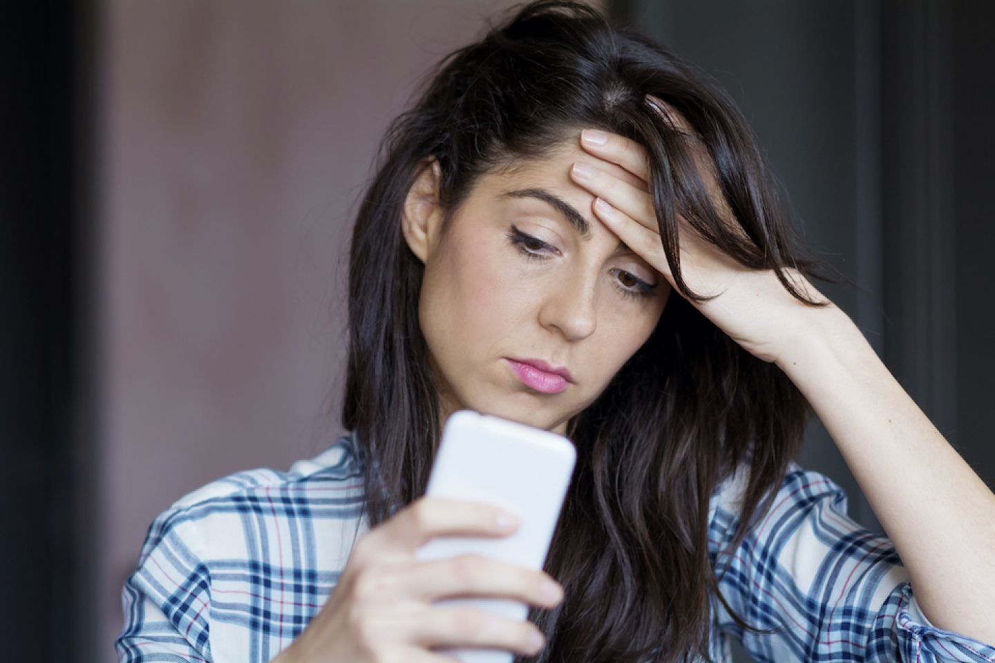 women stares at phone looking stressed