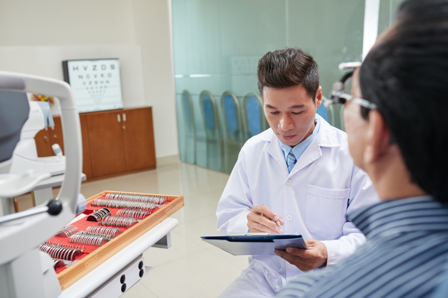 optometrist reading medical card of male patient