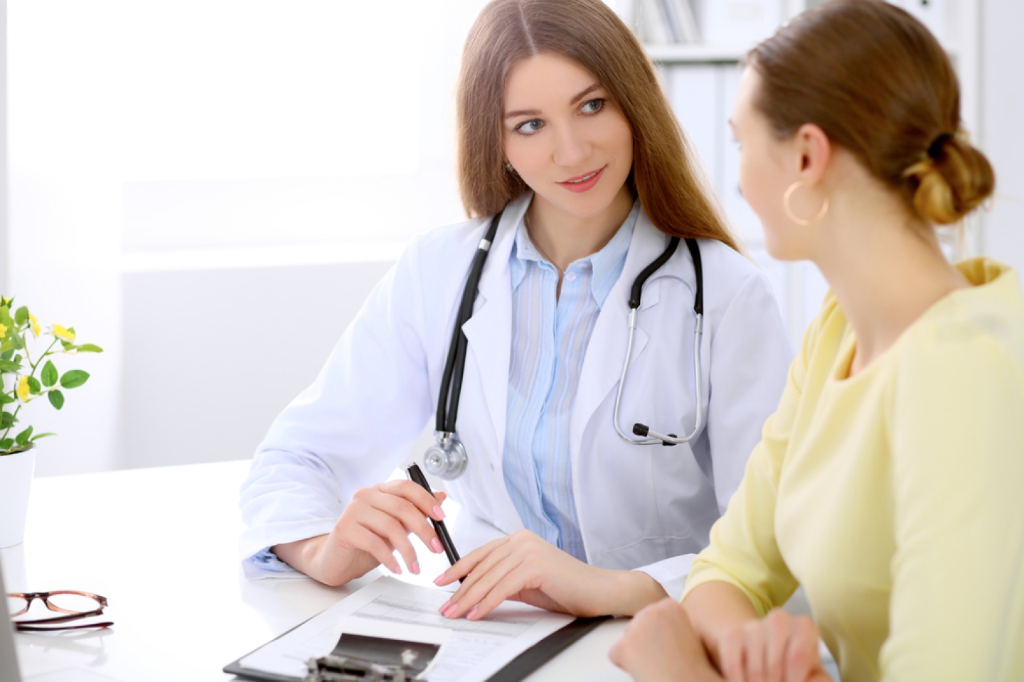 Doctor and patient sitting at the desk near window