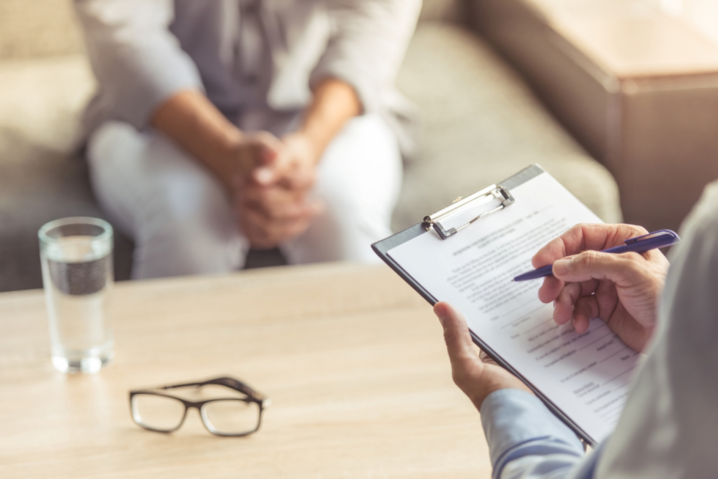 Doctor is making notes while listening to his patient.