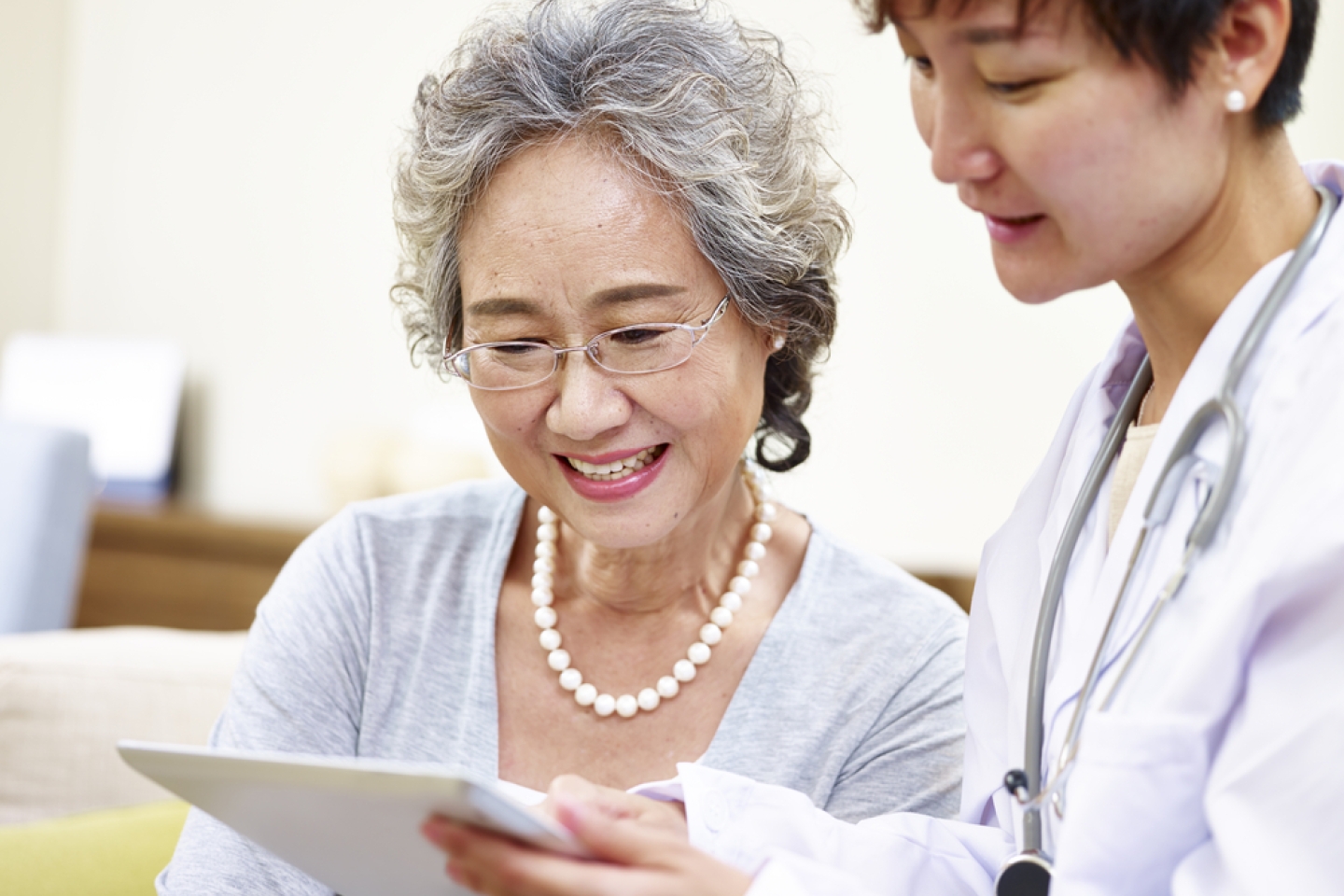 senior asian woman and family doctor having a discussing using tablet computer