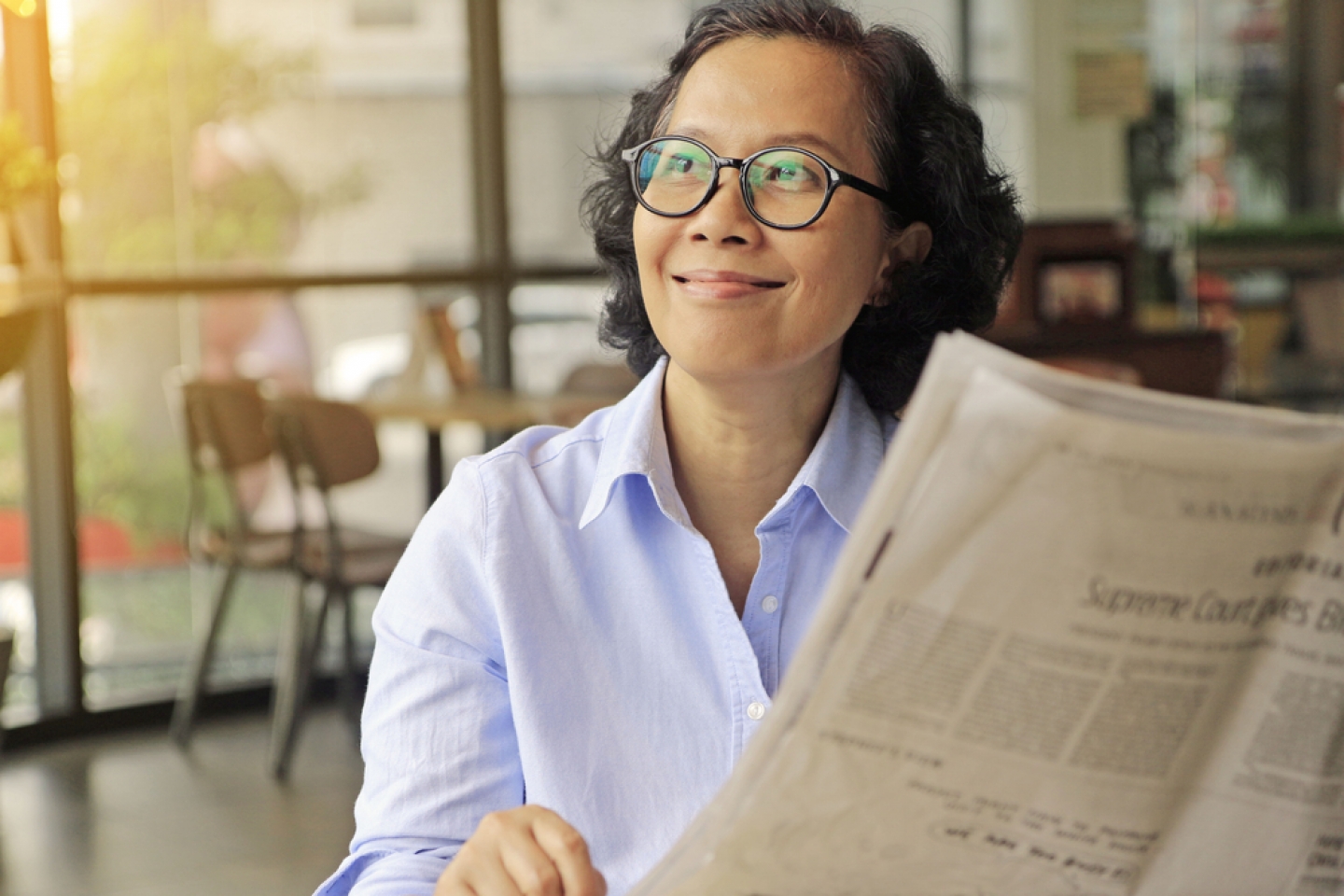 Asian middle age woman happy with a good news after read newspaper.