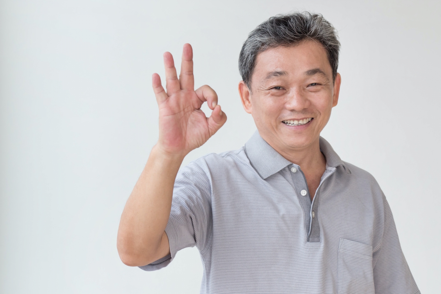 older asian man holds hand sign