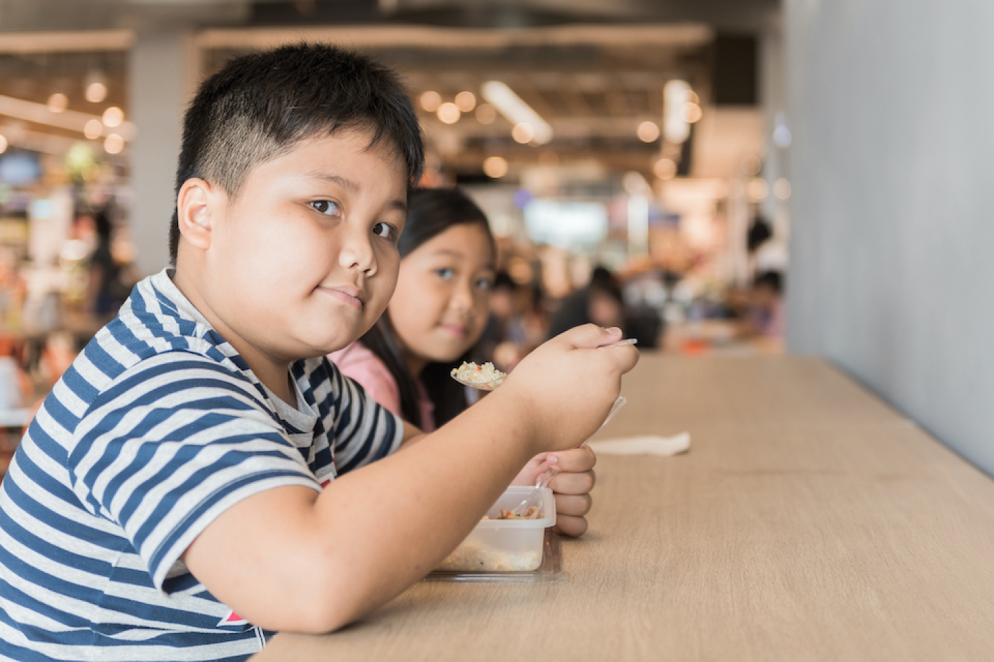obese child eating at food court