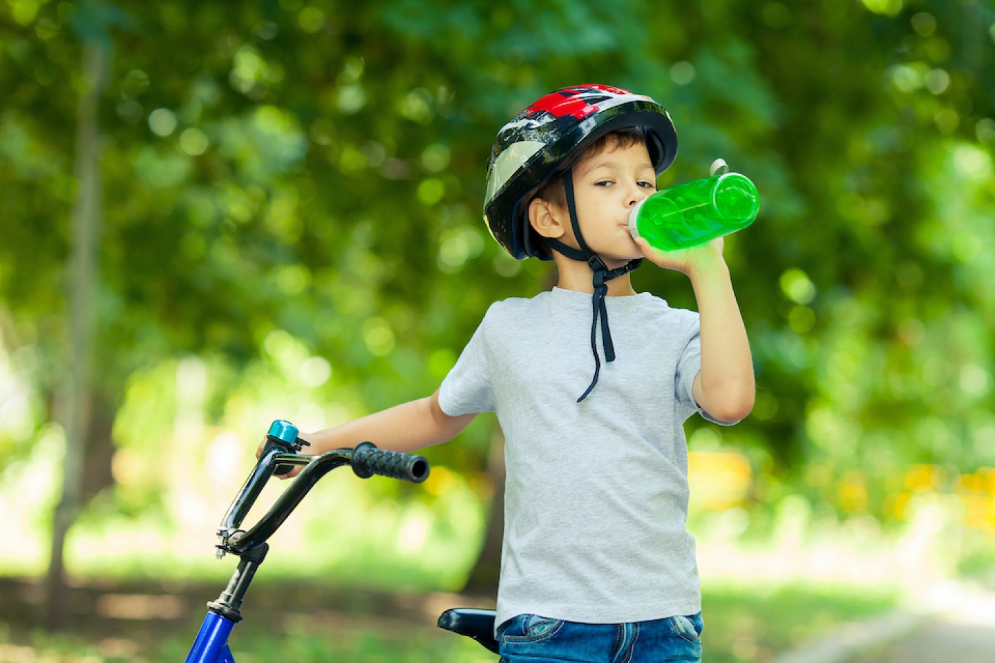 child on bike drinking water