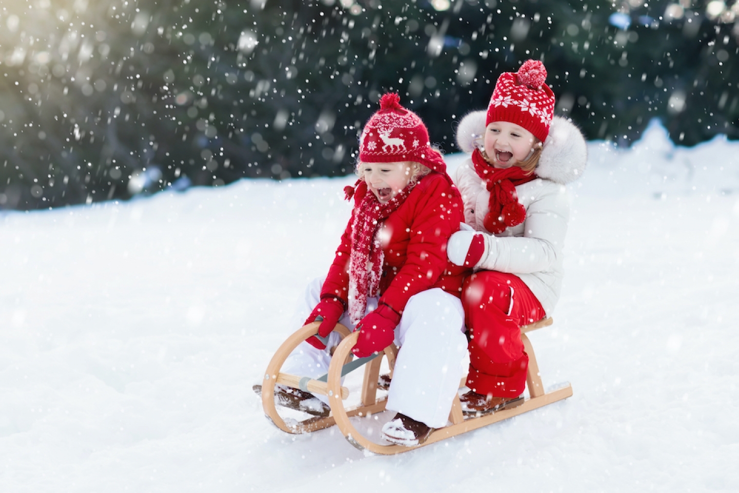 two kids sledding in the snow