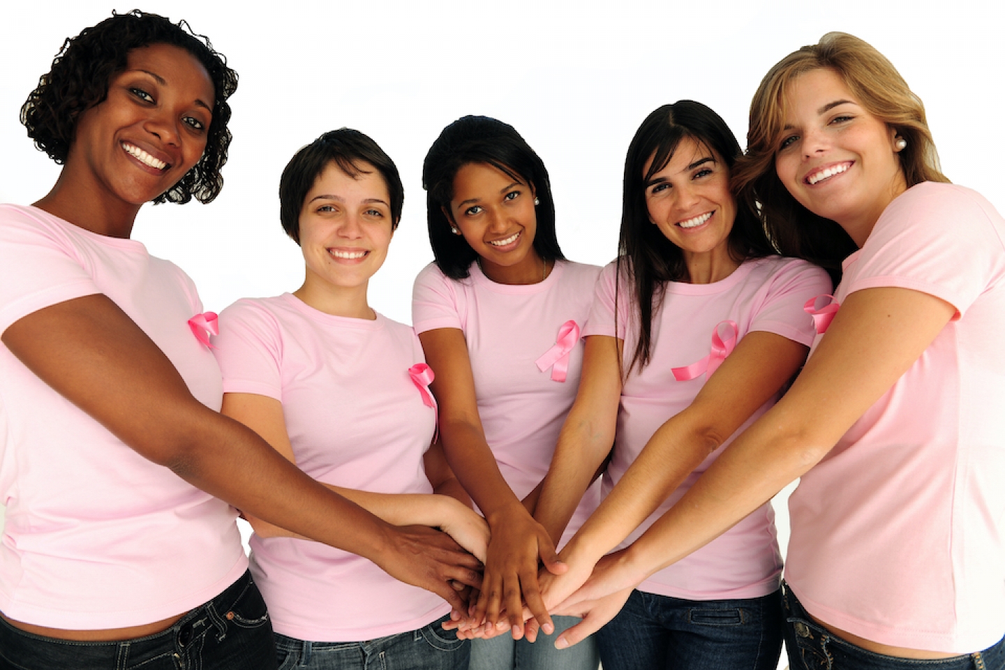 diverse women wearing pink ribbon with their hands together 