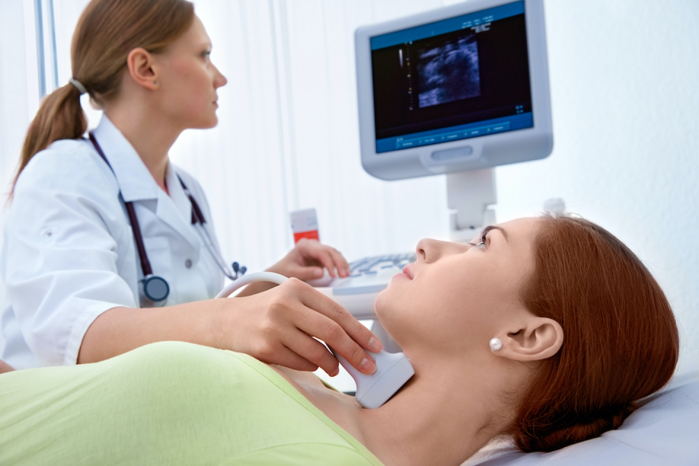 female doctor examining thyroid of female patient