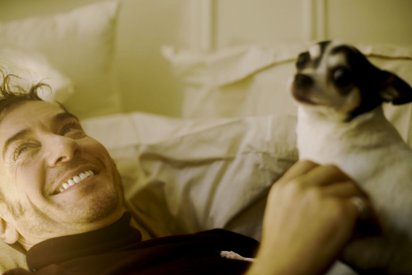 Feature patient Timothy is smiling with his dog sitting on his lap