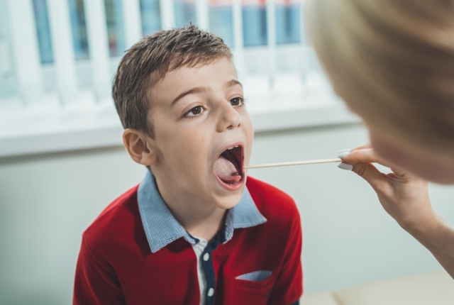 boy has strep throat. Children's ENT doctor examines  boy's throat. Children's diseases, medical examination.