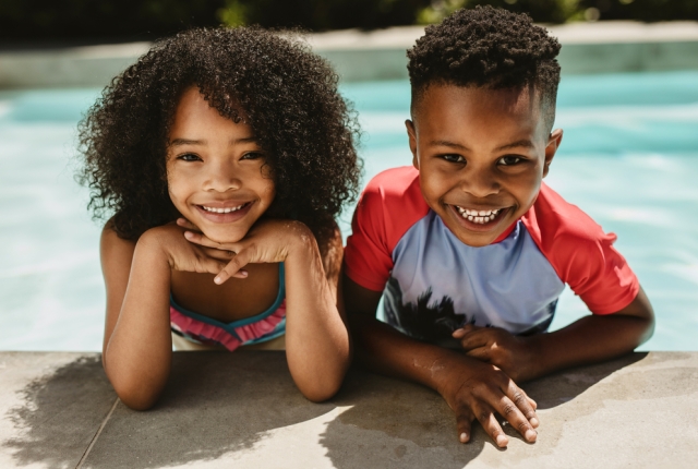 two smiling children by the pool