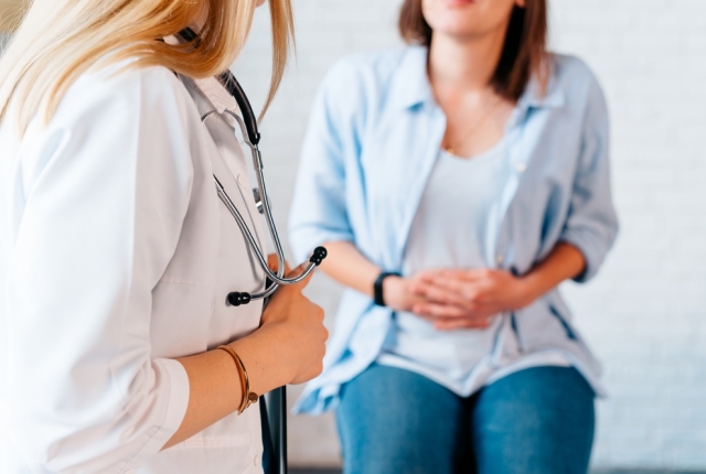 a woman in consultation with a doctor with abdominal pain