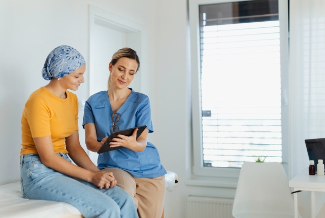 Teenage oncology patient talking with doctor. Oncologist treating teen girl with cancer and provide emotional support, helping her with anxiety and depression.