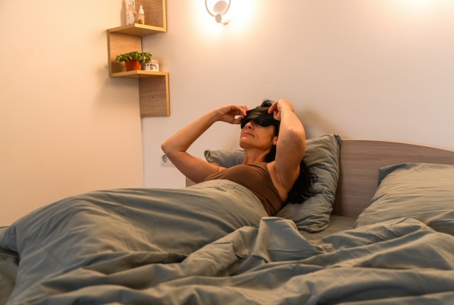 woman with blindfold trying to sleep in bed