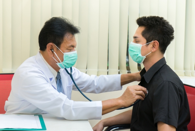 Senior Asian doctor examining male patient in the hospital.Doctor listening patient's heartbeat.