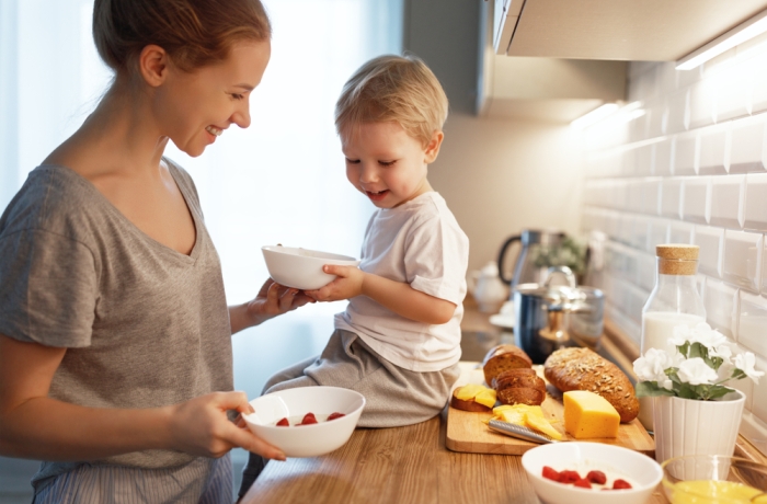 preparation of a family breakfast. mother and baby son cook porridge in morning