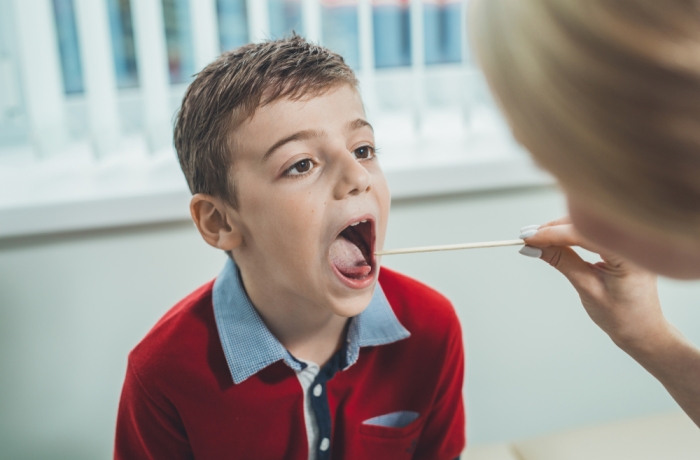 boy has strep throat. Children's ENT doctor examines  boy's throat. Children's diseases, medical examination.