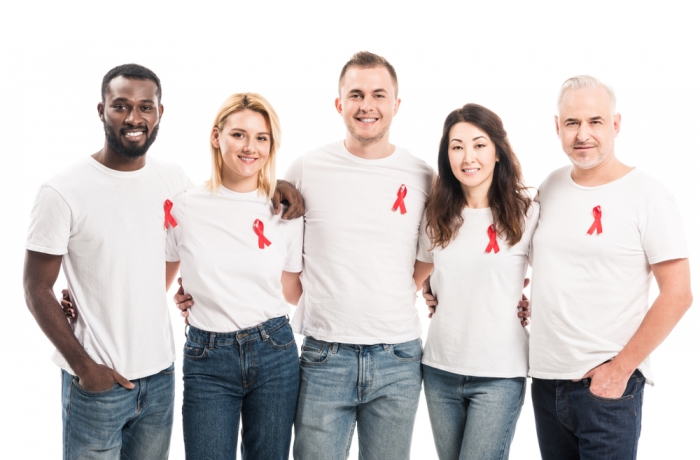 multiethnic group of people in blank white t-shirts with aids awareness red ribbons looking at camera isolated on white