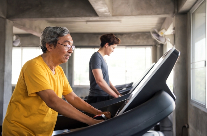 Healthy old man and American guy running on treadmill at fitness gym. family in sport center to exercise or workout for good health. Senior and young men exercise for Bodybuilding healthy lifestyle.