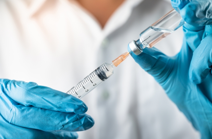Doctor, nurse, scientist, researcher hand in blue gloves holding flu, measles, coronavirus, covid-19 vaccine disease preparing for human clinical trials vaccination shot, medicine and drug concept.