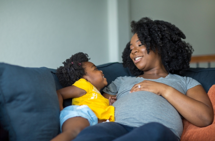 African American little girl talking with her pregnant mother.