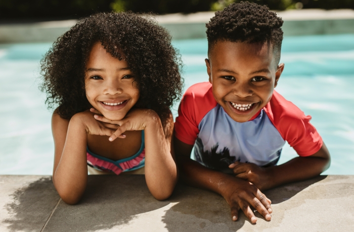 two smiling children by the pool
