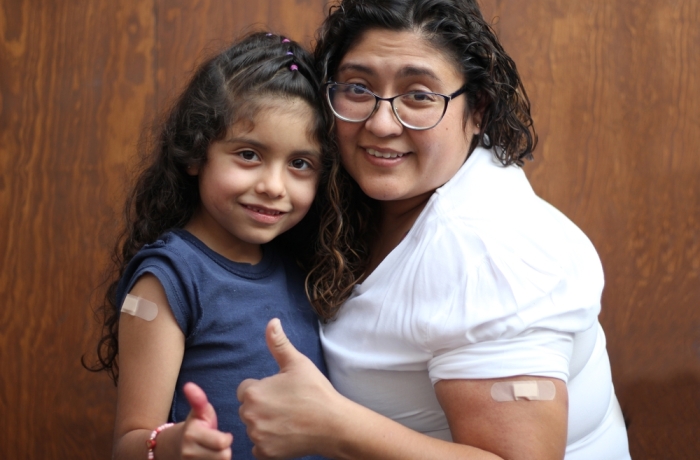 Happy and hugging Latin mom and daughter show their recently vaccinated arms against Covid-19 in the new normality due to the Coronavirus pandemic