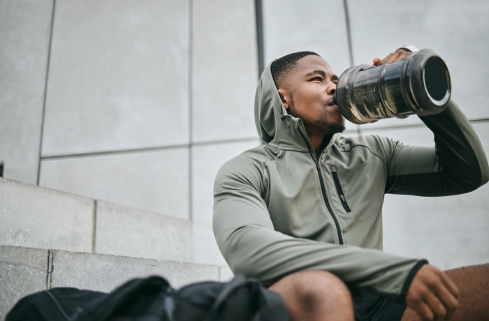 Fitness, relax or black man drinking water in training or exercise for body recovery or workout in Chicago, USA. Hydration, thirsty or tired healthy sports athlete drinks natural liquid in bottle