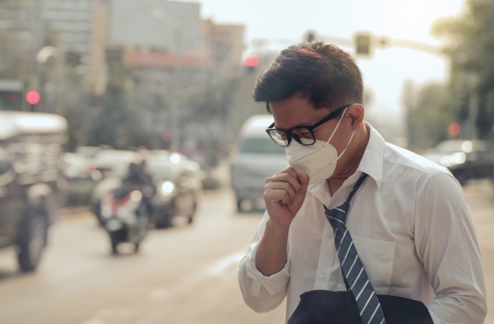 Business man wearing a mask and coughing on the street.