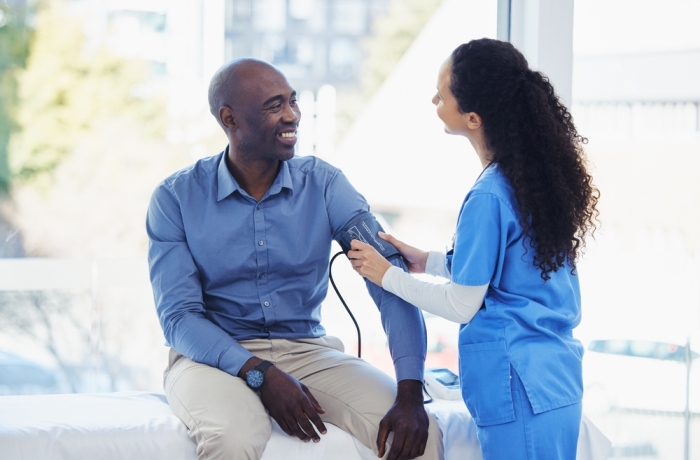 Black man, doctor and blood pressure healthcare in hospital for health insurance consultation. Patient and professional nurse woman talking about hypertension, wellness and advice for healthy life