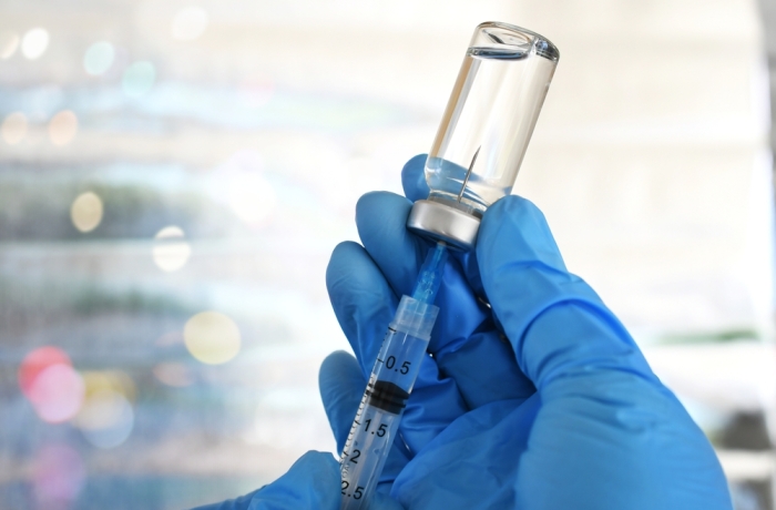 Medical personnel filling a syringe needle with generic vaccine booster from vial - flu shot RSV covid