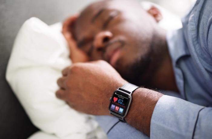 Man Sleeping With Smart Watch In His Hand Showing Heartbeat Rate
