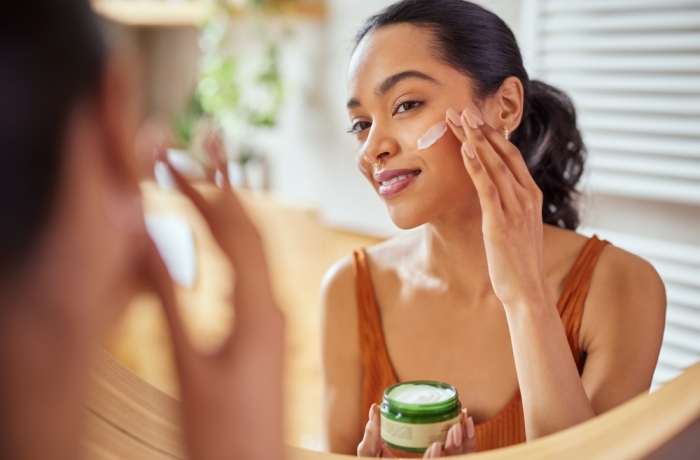 Woman caring of her beautiful skin on the face standing near mirror in the bathroom.