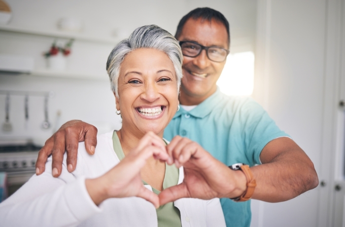 Heart hands, love and smile with portrait of old couple for support, happy and relax. Happiness, kindness and peace with senior man and woman and gesture at home for embrace, trust and retirement