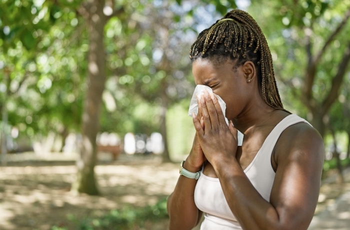 woman using tissue with pollen allergy at park