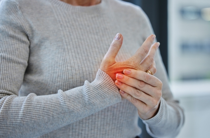 Mature, hands and pain with injury or arthritis in workplace from person, burnout and red glow in office. Tendinitis, parkinsons and muscle fatigue or carpal tunnel syndrome with inflammation.