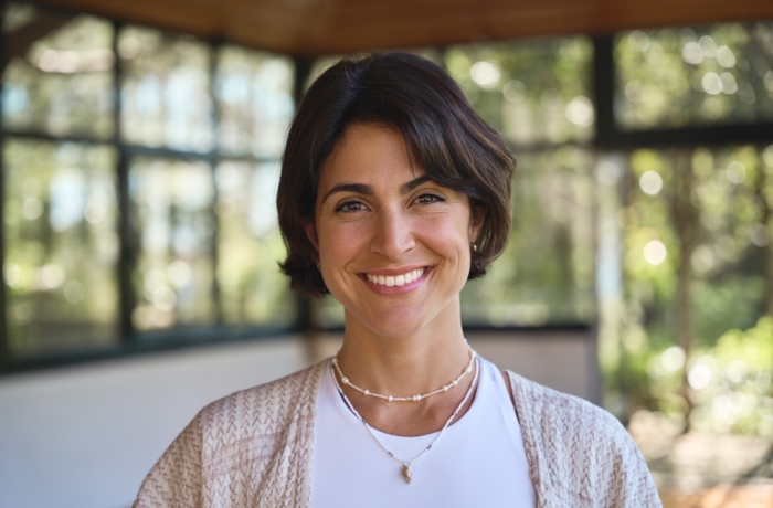 Young happy smiling confident Hispanic woman yoga coach instructor, holistic teacher looking at camera standing in yoga studio advertising retreat mind body health therapy. Close up portrait.
