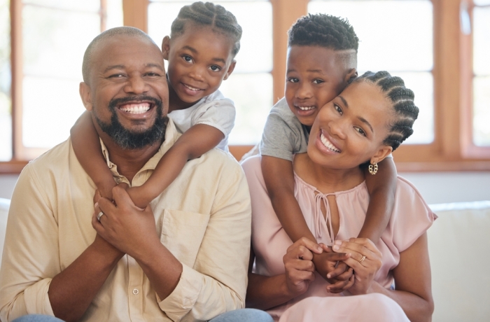 Hug, happy family and portrait in home on weekend with love for mom, dad and kids on couch. African man, woman and children on sofa for care, support and trust or bond together with smile and pride