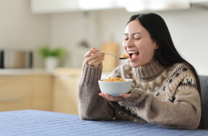 Happy asian woman eating cereals in winter in the kitchen at home