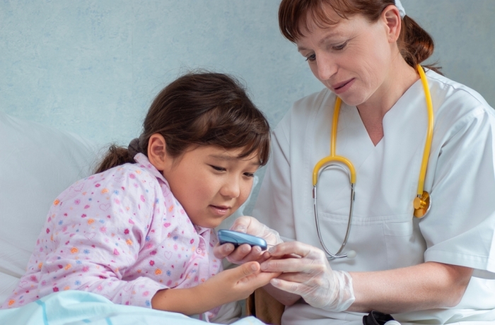 Asian girl at hospital getting her blood sugar measured by doctor or nurse during medical health check-up to prevent diabetes