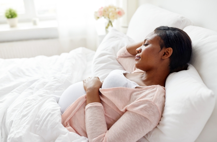 pregnant african american woman sleeping in bed at home