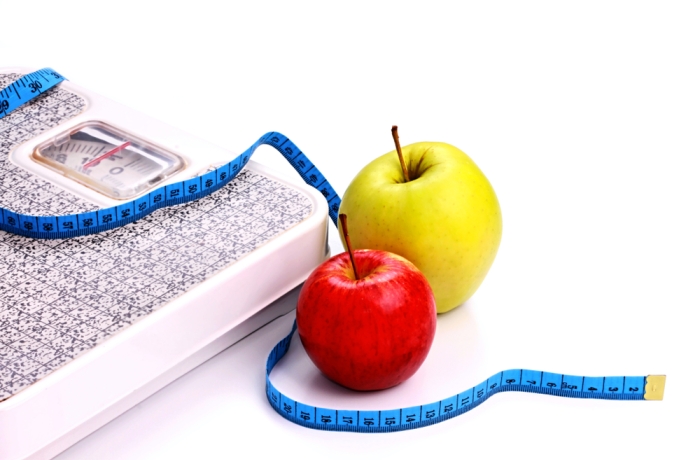 Loosing weight weighing scale and eating healthy in the new year starting with a delicious apple no people stock photo