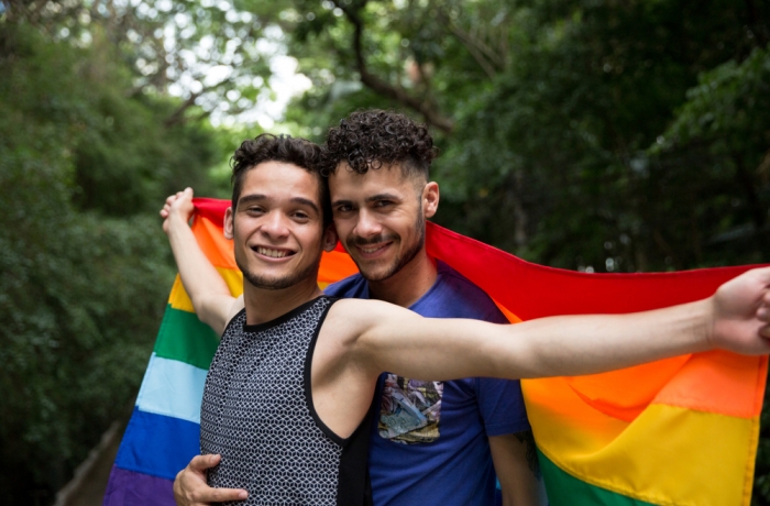 Gay Couple Embracing with Rainbow Flag in the Park
