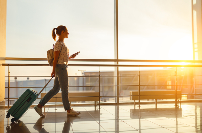 young woman goes at airport at window with a suitcase waiting for plan