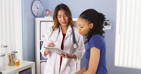 Female doctor with clipboard talks to patient