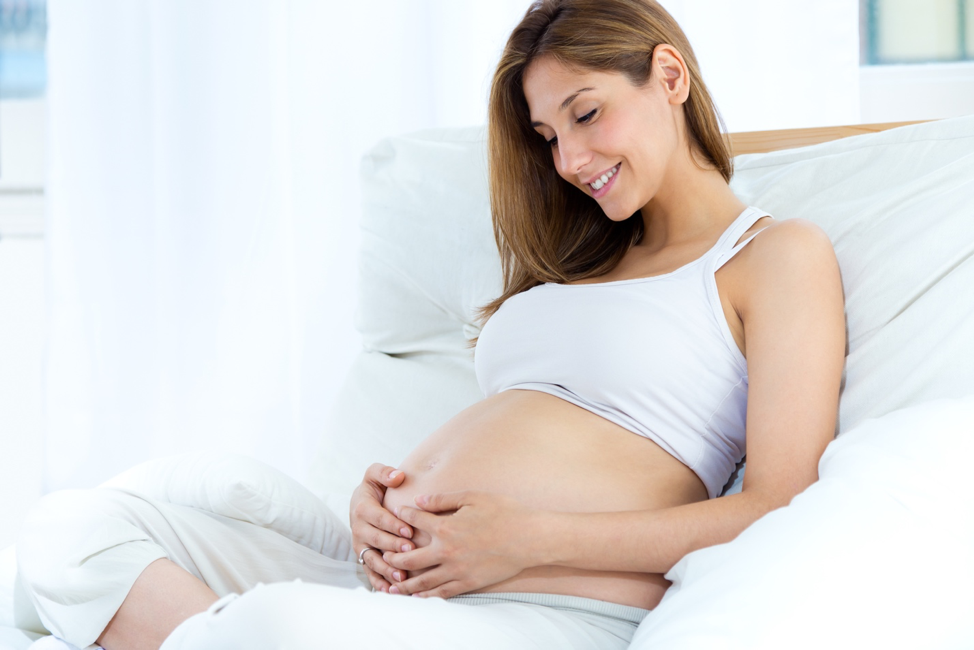 Pregnant woman holding and looking at belly.