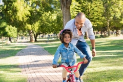 father teaching his son how to ride a bike